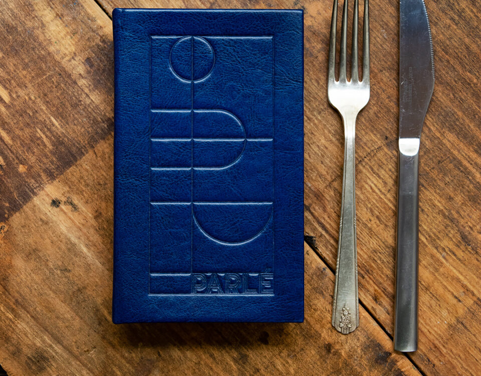 granatowe menu na stole, obok widelec i nóż